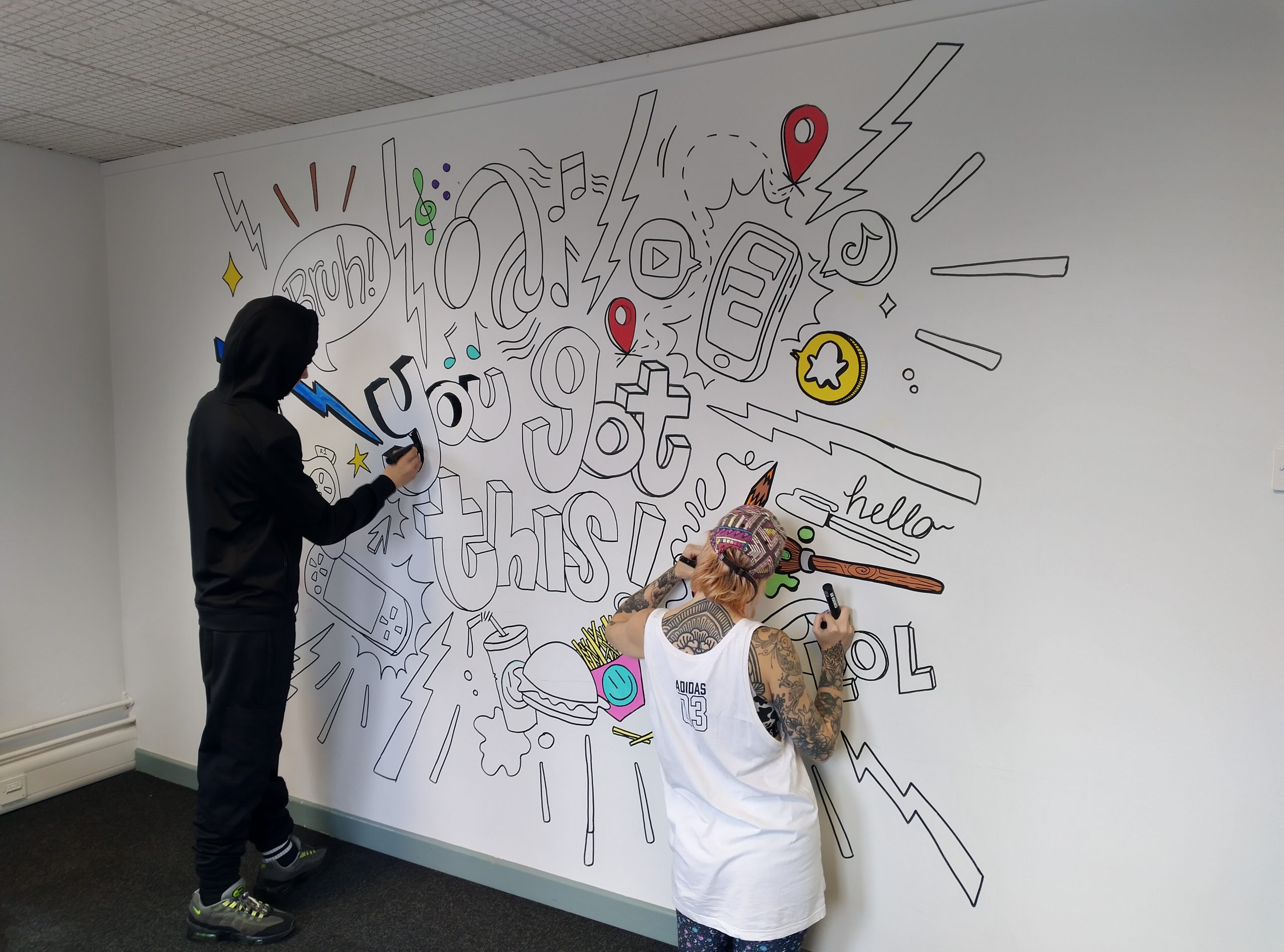 Two young people drawing a mural on a wall