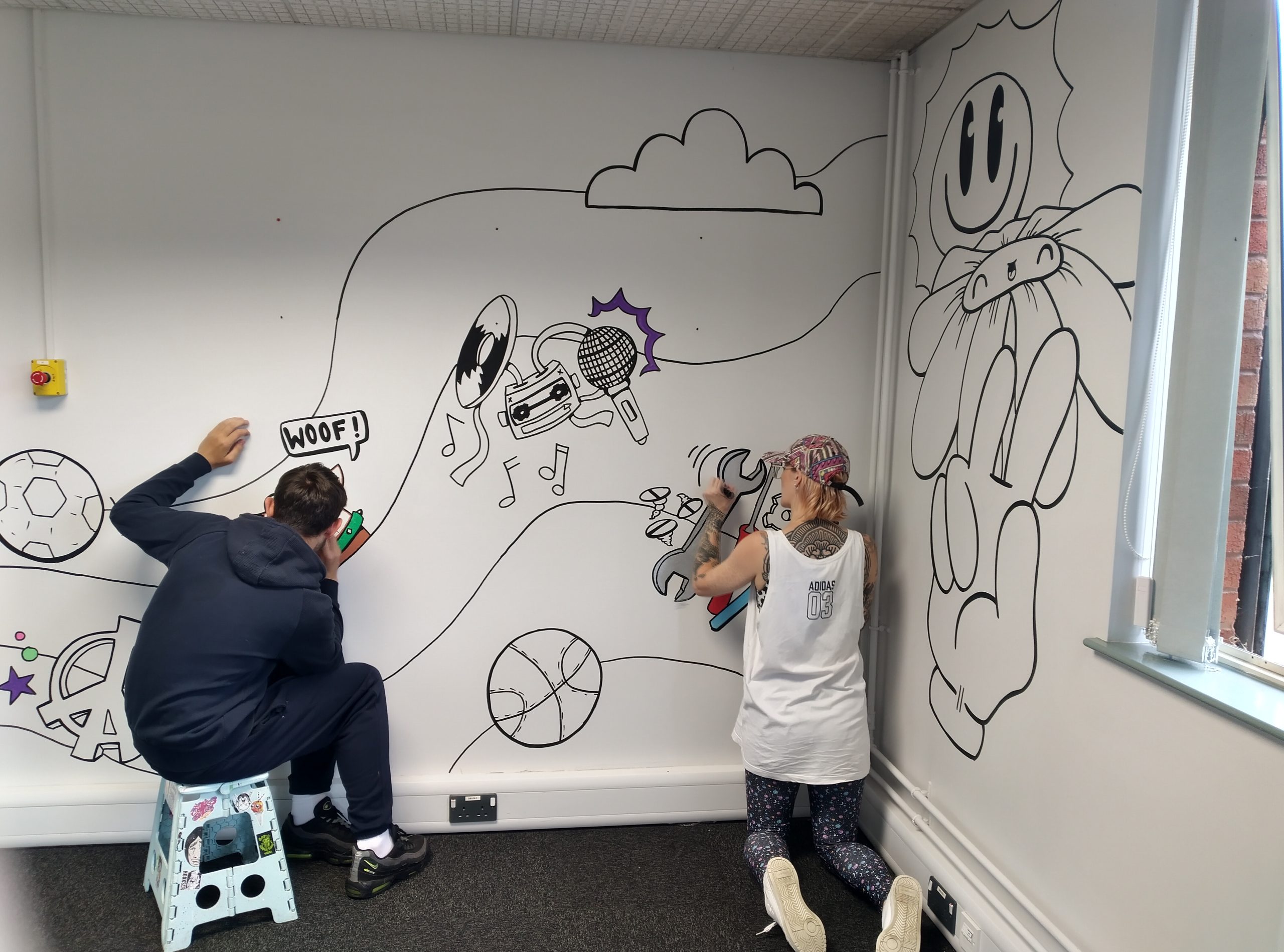 Two young people drawing a mural on a wall